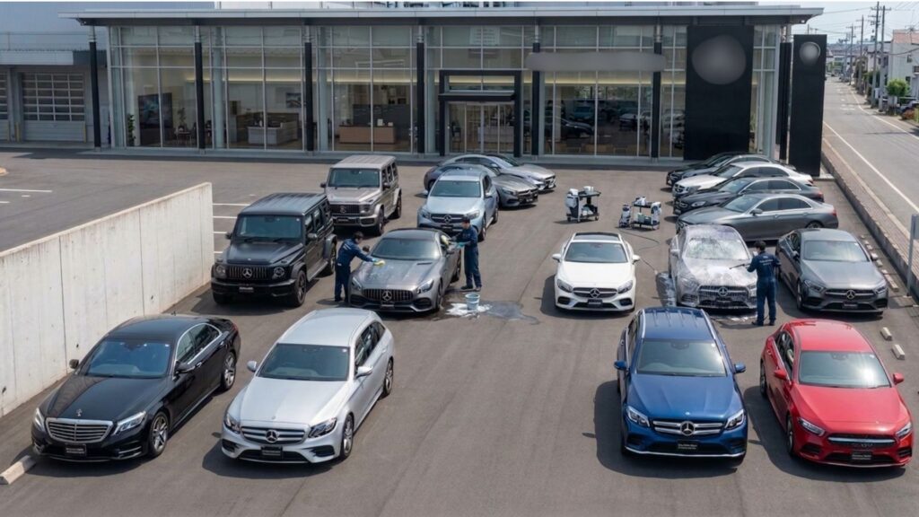 カーディーラーの展示場で、展示車両を並べたままスタッフが水なし洗車している様子