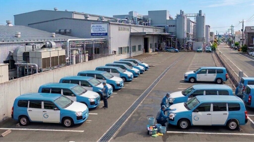 事業所の駐車場に並んだ社用車を、スタッフが水なし洗車している様子